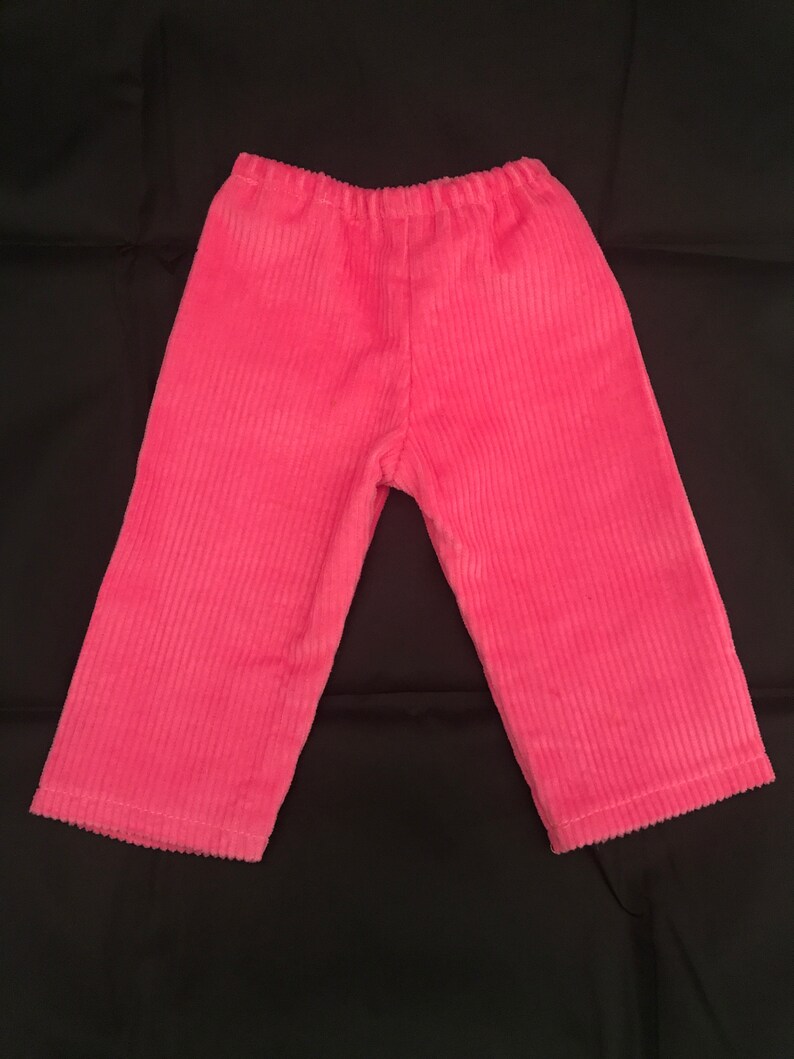 May include: Pink corduroy trousers with a wide leg and elastic waistband.