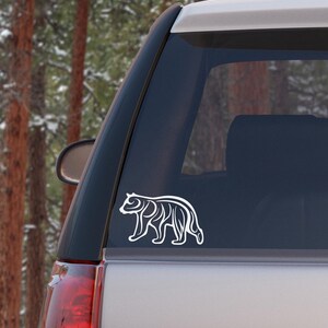 May include: White vinyl decal of a stylized bear silhouette on a silver car window.