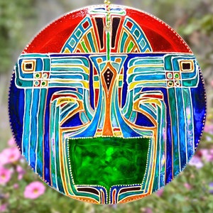 May include: A round stained glass suncatcher with a geometric design in shades of red, blue, green, and yellow. The suncatcher features a central green circle surrounded by a blue and yellow design.