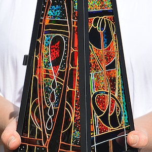 May include: A black metal lantern with stained glass panels featuring geometric designs in red, orange, yellow, blue, and green.