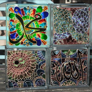 May include: Four glass blocks with colorful stained glass designs. The designs include Arabic calligraphy, a peacock feather pattern, and a floral pattern.