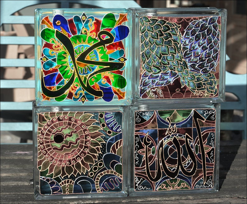 May include: Four glass blocks with colorful stained glass designs. The designs include Arabic calligraphy, a peacock feather pattern, and a floral pattern.