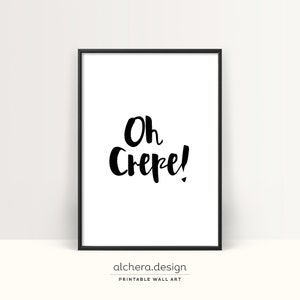 May include: A rectangular wall art print in a thin black frame featuring a white background with the black hand-lettered text Oh Crepe! centered in the middle. The design uses a bold brush-style font to display the phrase clearly on the paper.