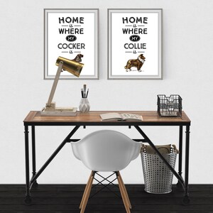 May include: Two framed prints with dog illustrations and the text "Home is Where My Cocker is" and "Home is Where My Collie is" hang above a desk. The desk has a wooden top, black metal legs, and a brass desk lamp.