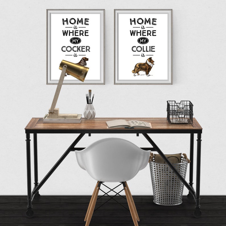 May include: Two framed prints with dog illustrations and the text "Home is Where My Cocker is" and "Home is Where My Collie is" hang above a desk. The desk has a wooden top, black metal legs, and a brass desk lamp.