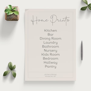 A white sheet of paper with "Home Prints" at the top and a list of rooms below, next to a pen and small plant.