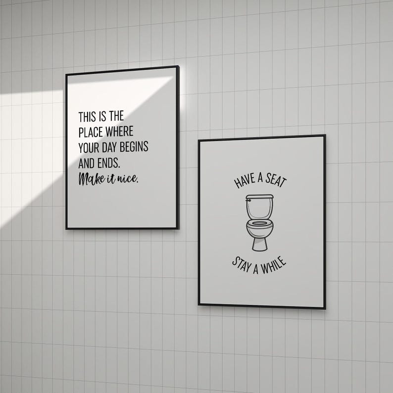 Two black-framed typographic and illustrated wall art prints hanging on white tiled walls.