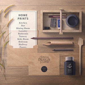 Puede incluir: Una vista a&eacute;rea de art&iacute;culos de papeler&iacute;a y decoraci&oacute;n del hogar sobre una superficie de madera. Incluye una lista titulada "HOME PRINTS", sobres, una caja de madera con art&iacute;culos de papeler&iacute;a, un frasco de tinta y una esp&aacute;tula de madera. El texto "Pilchera DESIGN Posters" es visible.