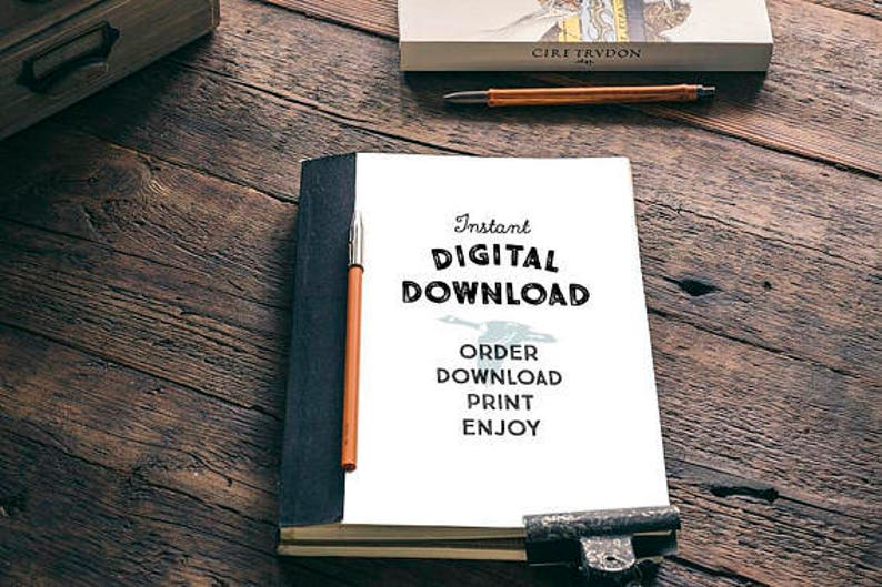 May include: A white paper with the text "Instant DIGITAL DOWNLOAD" and instructions to "ORDER DOWNLOAD PRINT ENJOY" is held open by a metal clip. A pen rests on the paper, and a book and wooden box are in the background.