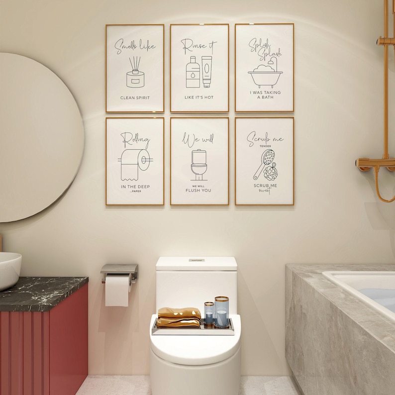 A bathroom with a toilet, a sink, and six framed black and white line art prints on a light-colored wall.