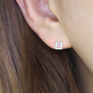 Peut inclure: Une paire de boucles d'oreilles clous carrées en argent avec un centre creux.