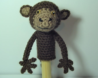 May include: A handmade crochet monkey puppet with a brown body, head, and arms. The monkey has a tan face, large ears, and golden eyes. The puppet is attached to a wooden dowel, perfect for imaginative play or as a decorative item.