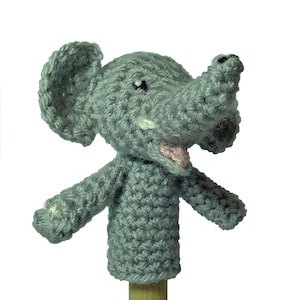 May include: Gray crocheted finger puppet shaped like an elephant with a pink tongue sticking out. The elephant has a small black eye and a white tusk.