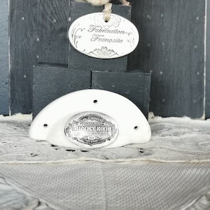 Peut inclure: Un panneau de buanderie en céramique blanche en forme de demi-lune avec une plaque en métal argenté qui indique "Self-Service Open 24 Hours Laundry Room 25c Per Load".