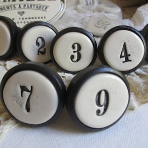 May include: Nine black and white ceramic knobs with numbers 1 through 9. The knobs have a black rim and a white center with black numbers.