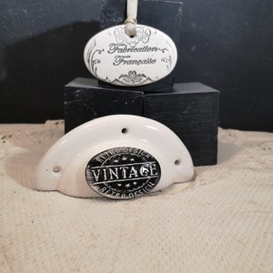 May include: White ceramic wall hook with a black and white round label that says "Retro Design Vintage Retro Design". A white oval ceramic tag with the text "Fabrication Française" hangs above the hook.