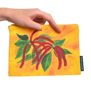 Peut inclure: Une pochette jaune à fermeture éclair avec une illustration vibrante de fleurs rouges allongées et de feuilles vertes. L'œuvre est sur un fond orange-jaune chaud. La pochette a une petite étiquette bleue avec du texte blanc.