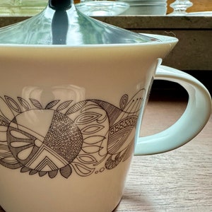 May include: White ceramic teapot with a black and white abstract design. The teapot has a lid and a handle.