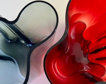 May include: Two vases, one red and one blue, with a unique, organic, wavy design. The vases are made of glass and have a glossy finish.