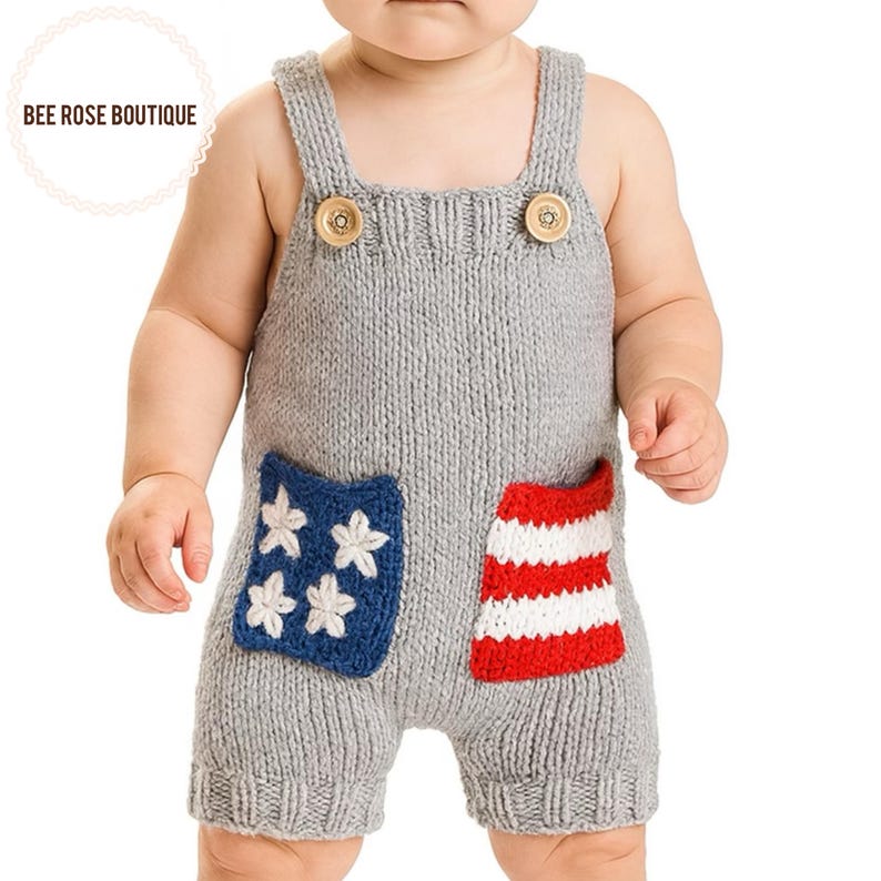 May include: Gray knitted baby romper with wooden buttons and patriotic pocket designs. One pocket features white stars on a blue background, and the other has red and white stripes. The text "BEE ROSE BOUTIQUE" is in the upper left corner.
