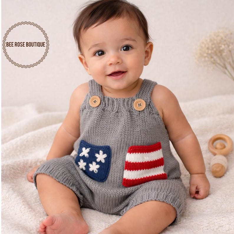 May include: A gray knitted baby romper with wooden button closures and pockets. One pocket features white stars on a blue background, the other red and white stripes. The romper is designed for a baby.