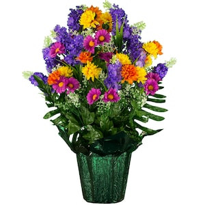 May include: A green planter with a bouquet of artificial flowers. The flowers are purple, pink, yellow, and orange. The planter has a textured surface.