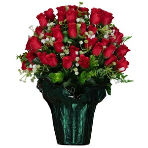 May include: A large, dense bouquet of deep red artificial roses arranged in a rounded shape. The arrangement includes small white filler flowers and green foliage, all held within a dark, metallic green crinkled paper wrapping at the base.