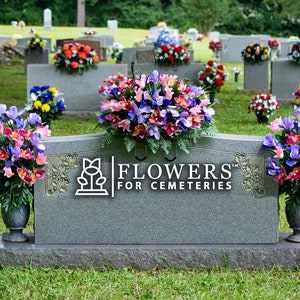 May include: A gray granite headstone with a vase of artificial flowers on each side. The headstone has the words "Flowers for Cemeteries" engraved on it.