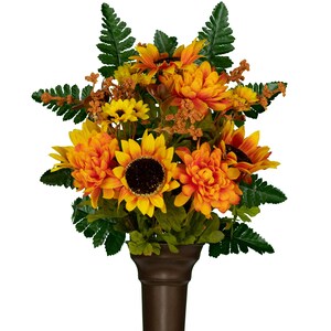 May include: A floral arrangement featuring bright yellow and orange sunflowers, orange dahlias, and green fern leaves. The bouquet includes small brown textured filler sprigs and is displayed in a dark brown, tapered, cylindrical vase.
