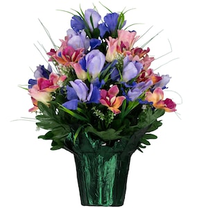 May include: A vibrant floral arrangement featuring a mix of colorful irises, orchids, and other flowers in shades of purple, pink, and orange. The flowers are arranged in a dark green, textured pot, creating a lively and decorative display.