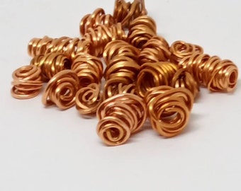 May include: A pile of copper wire coils, each coil is a spiral of wire, the coils are a light copper color.