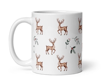 May include: A white ceramic mug with a black handle and the text "But First, Coffee" in a bold, black font. The mug is set against a blurred background, suggesting a cozy setting.