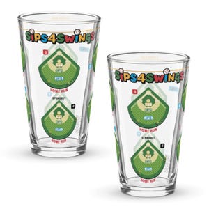 May include: Two clear pint glasses with a baseball field design. The glasses have the text "SIPS4SWINGS" at the top and a baseball field graphic in the center. The baseball field graphic includes the words "HOME RUN" and "STRIKEOUT".