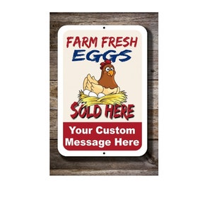 May include: A white metal sign with red and blue text that reads "Farm Fresh Eggs Sold Here" with a cartoon chicken sitting on a nest of eggs. The sign also has the text "Your Custom Message Here".
