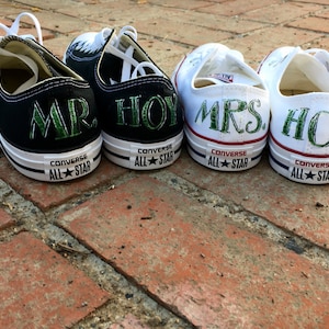 May include: A pair of white canvas sneakers with green text that reads "MRS. HOY" and a pair of black canvas sneakers with green text that reads "MR. HOY".