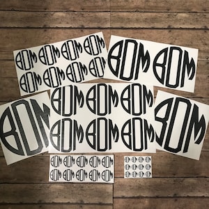 Pode incluir: Um conjunto de 12 adesivos de vinil branco com letras pretas. Os adesivos apresentam as letras "BOD" em um círculo. Os adesivos estão dispostos em filas de três, com quatro filas no total.