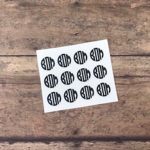 May include: A sheet of white paper with twelve black monogram stickers. Each sticker features the letters "BOM" in a circle.