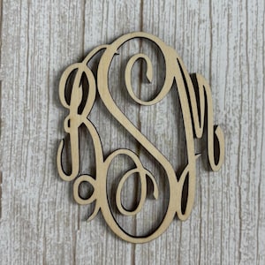 Puede incluir: Un recorte de monograma de madera de color claro con tres letras entrelazadas en cursiva. El diseño consta de una letra central grande flanqueada por dos letras más pequeñas, todas conectadas por líneas fluidas y decorativas con un acabado de madera natural.