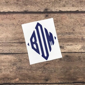 Pode incluir: Um adesivo branco com um monograma azul marinho das letras "BOM" em forma de diamante.