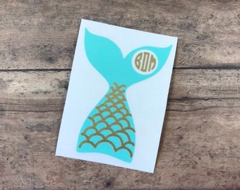May include: A turquoise mermaid tail decal with gold scales and a white circle with the monogram "BOM" in gold.