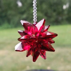 May include: A red crystal starburst car charm hanging from a clear beaded string.