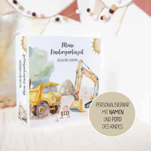 Könnte beinhalten: Ein weißer Ordner mit dem Titel Meine Kindergartenzeit und einer Aquarellillustration eines gelben Muldenkippers und Baggers auf einer Baustelle. Der Buchrücken zeigt den Namen Anton Mustermann und den Titel. Ein beiger Textkreis ist zu sehen.
