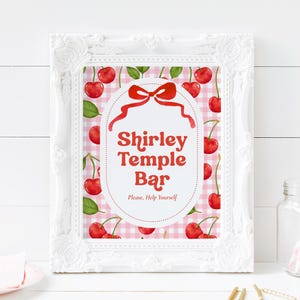 May include: A white ornate picture frame containing a sign with a pink and white gingham background, red cherries, and a red bow. The text reads Shirley Temple Bar, Please, Help Yourself in a red font centered within an oval border.