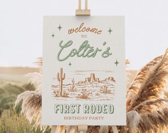 Może przedstawiać: Biały znak z brązowym i zielonym tekstem, na którym widnieje napis "Welcome to Colter's First Rodeo Birthday Party". Znak zawiera rysunek pustynnego krajobrazu z kaktusami i górami.