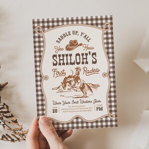 Op de afbeelding: Een rechthoekige uitnodigingskaart met een bruin-witte vichy-ruitrand en een cr&egrave;mekleurig middenpaneel. De tekst luidt: SADDLE UP, Y'ALL, Yee Haw, SHILOH'S First Rodeo, Wear Your Best Western Gear, JAN 25, 2:00 PM, en de evenementgegevens.