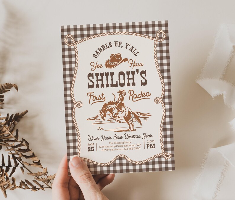 Op de afbeelding: Een rechthoekige uitnodigingskaart met een bruin-witte vichy-ruitrand en een cr&egrave;mekleurig middenpaneel. De tekst luidt: SADDLE UP, Y'ALL, Yee Haw, SHILOH'S First Rodeo, Wear Your Best Western Gear, JAN 25, 2:00 PM, en de evenementgegevens.