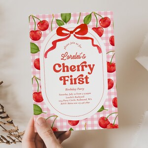 May include: A pink and white gingham patterned invitation with watercolor cherries and green leaves. The invitation reads "Lorelei's Cherry First Birthday Party" in red script and bold font. Includes event details.