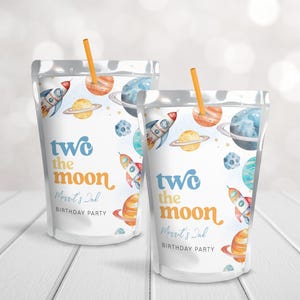 Op de afbeelding: Twee doorzichtige plastic zakjes met rietjes, met een ruimtethema met raketten, planeten en sterren. De zakjes hebben de tekst "Two the Moon" en "Merit's 2nd Birthday Party" erop gedrukt.