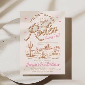 May include: A rectangular birthday invitation card on a light cream background featuring a brown cowboy hat and rope text that reads This Ain't My First Rodeo it's my 2nd! with pink stars and text Georgia's 2nd Birthday and event details.