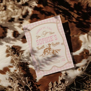 May include: A rectangular invitation card with a pink and white gingham border and a rope graphic. The text reads: SADDLE UP, Y'ALL, Yee Haw, SOPHIE'S Fourth Rodeo, Time for Pony Rides & Games, 2 to 4 PM, JAN 25, The Rustling Home, 1234 Roundup Circle Redmond, WA, RSVP: Kaylee text 123-456-7890.